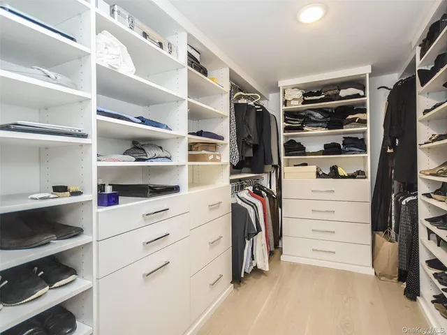 a view of walk in closet with clothes and shoes