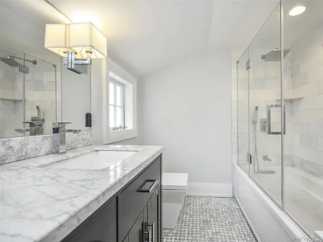 a bathroom with a granite countertop sink a toilet a mirror and shower