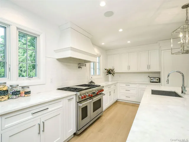 a kitchen with a stove white cabinetry and a sink