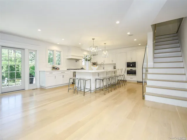 a living room with couches and kitchen view with wooden floor