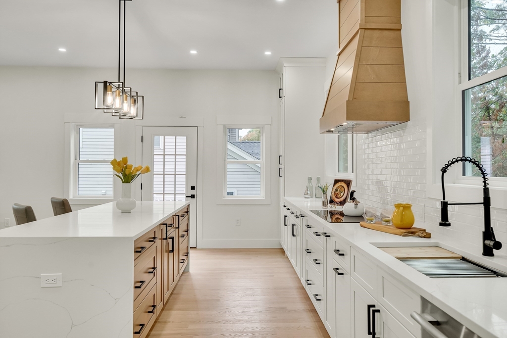 22 Estabrook Road Lexington, MA 02421 - Photo 14 of 36 a kitchen with stainless steel appliances a sink dishwasher a stove a dining table and chairs with wooden floor