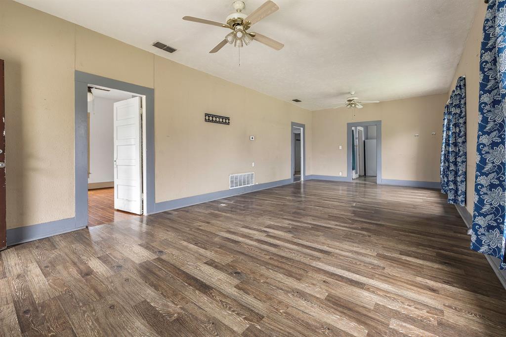 719 West Tarleton Street Stephenville, TX 76401 - Photo 5 of 30 a view of an empty room with wooden floor and a ceiling fan