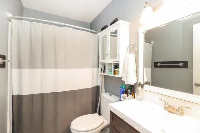 a bathroom with a toilet sink vanity granite and a shower