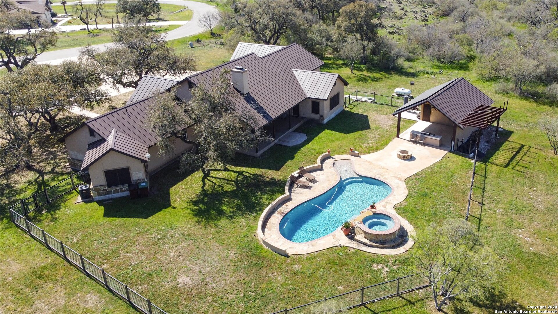 an aerial view of a house with swimming pool and big trees