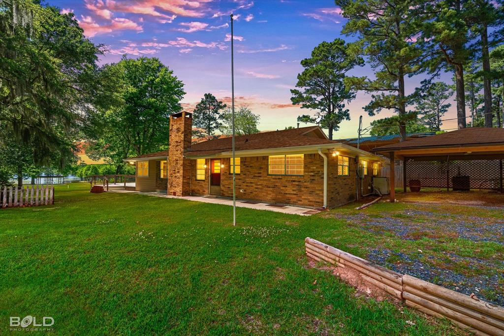 225 Marie Road Ringgold, LA 71068 - Photo 6 of 40 Brick ranch-style residence featuring a prominent brick chimney, an attached carport, and a spacious green lawn