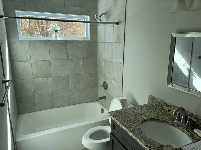 a bathroom with a granite countertop sink toilet and bathtub