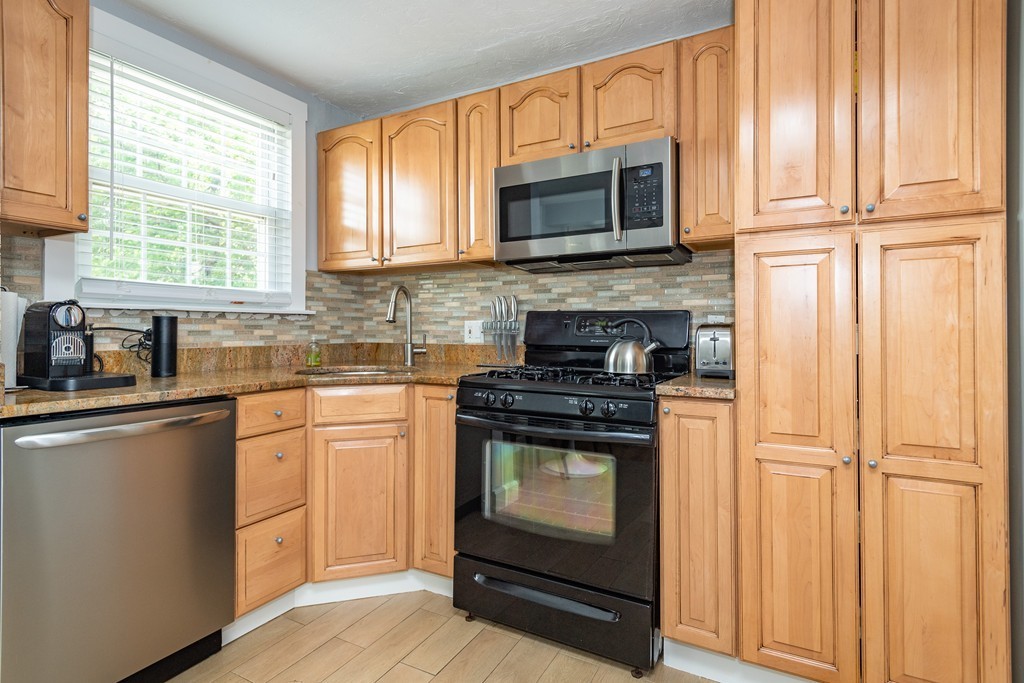 440 Adams Street, Unit 1 Boston, MA 02122 - Photo 4 of 14 a kitchen with granite countertop wooden cabinets stainless steel appliances and a window