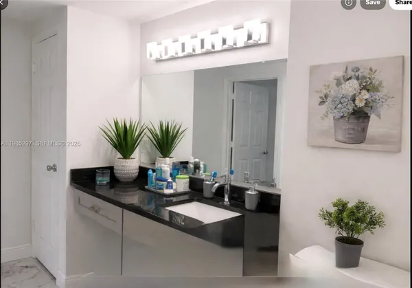 a bathroom with a granite countertop sink a mirror and a potted plant