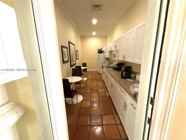 a large white kitchen with sink a refrigerator and a window