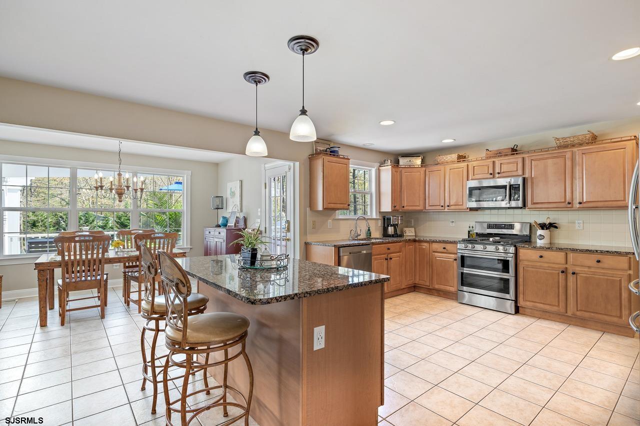344 Old New York Road Port Republic, NJ 08241 - Photo 53 of 99 a kitchen with stainless steel appliances granite countertop a stove top oven a sink a dining table and chairs with wooden floor
