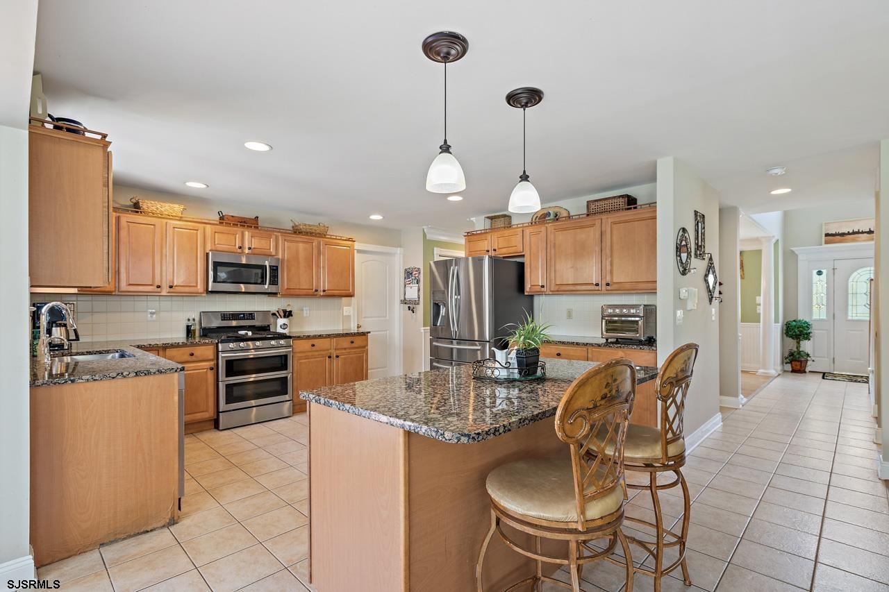 344 Old New York Road Port Republic, NJ 08241 - Photo 54 of 99 a kitchen with stainless steel appliances granite countertop a stove top oven a refrigerator a sink a dining table and chairs with wooden floor