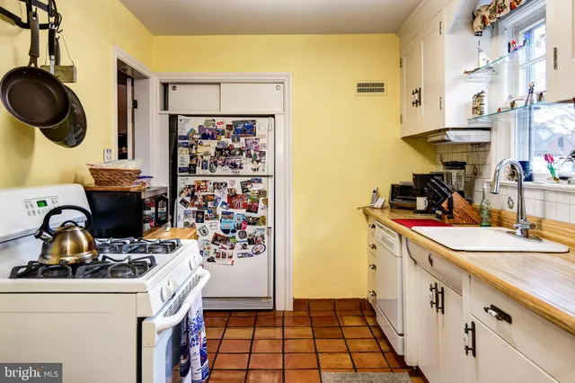 a kitchen with a sink and a stove with wooden floor
