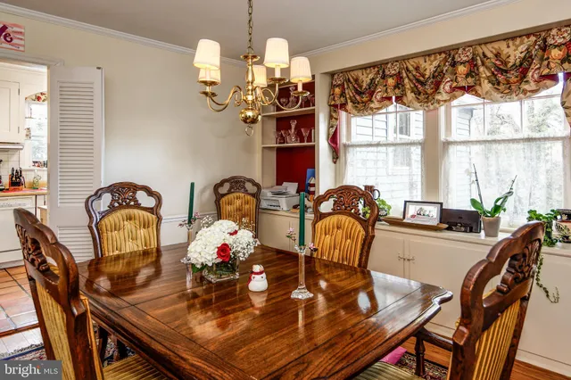 a view of a dining room with furniture a chandelier and large windows