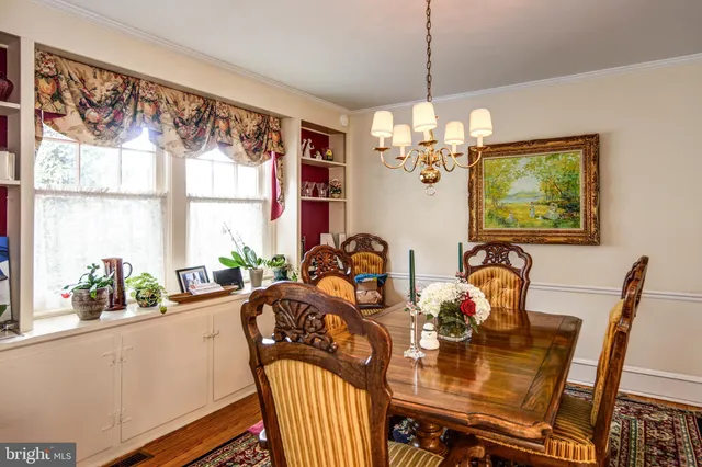 a view of a dining room with furniture a chandelier and large windows