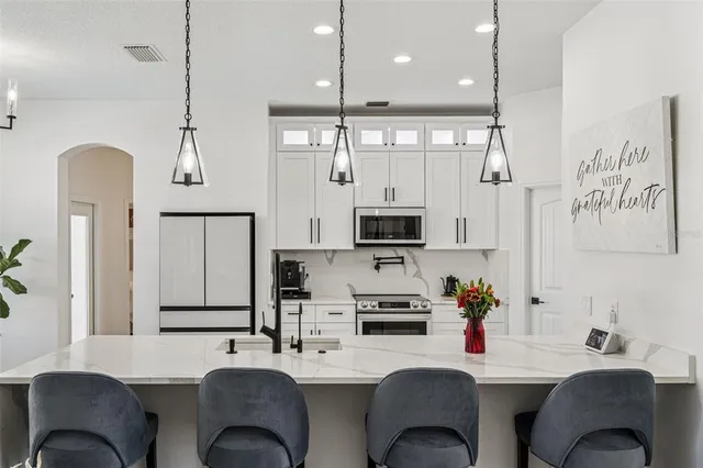 a kitchen with stainless steel appliances kitchen island granite countertop a sink a stove a dining table and chairs