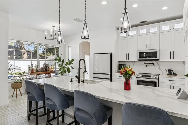 a kitchen with stainless steel appliances a refrigerator a stove a sink and chairs