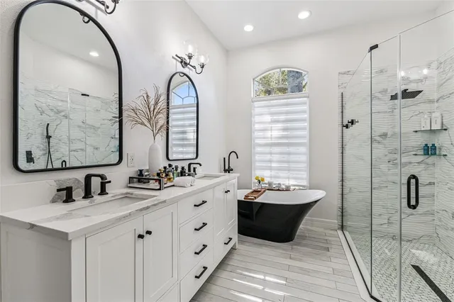 a bathroom with a double vanity sink mirror and bathtub