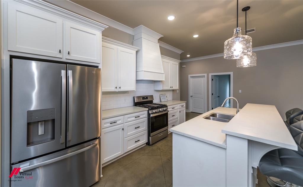 1320 Fuller Cemetery Road Minden, LA 71055 - Photo 20 of 40 Modern kitchen featuring white shaker cabinetry, stainless steel appliances, a subway tile backsplash, and an island with an undermount sink and pendant lighting