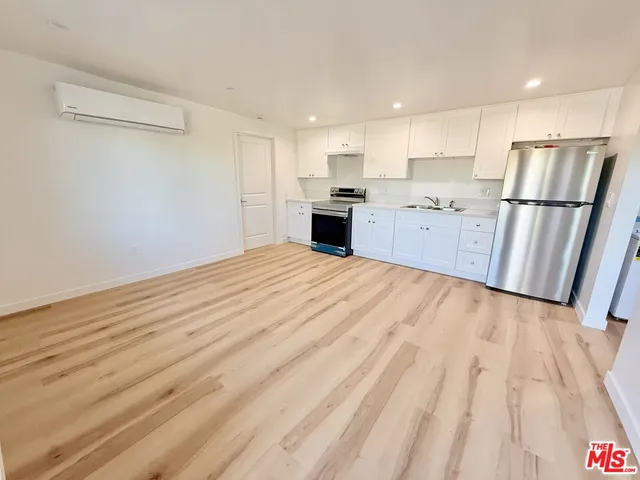 a large kitchen with a refrigerator a stove top oven and white cabinets