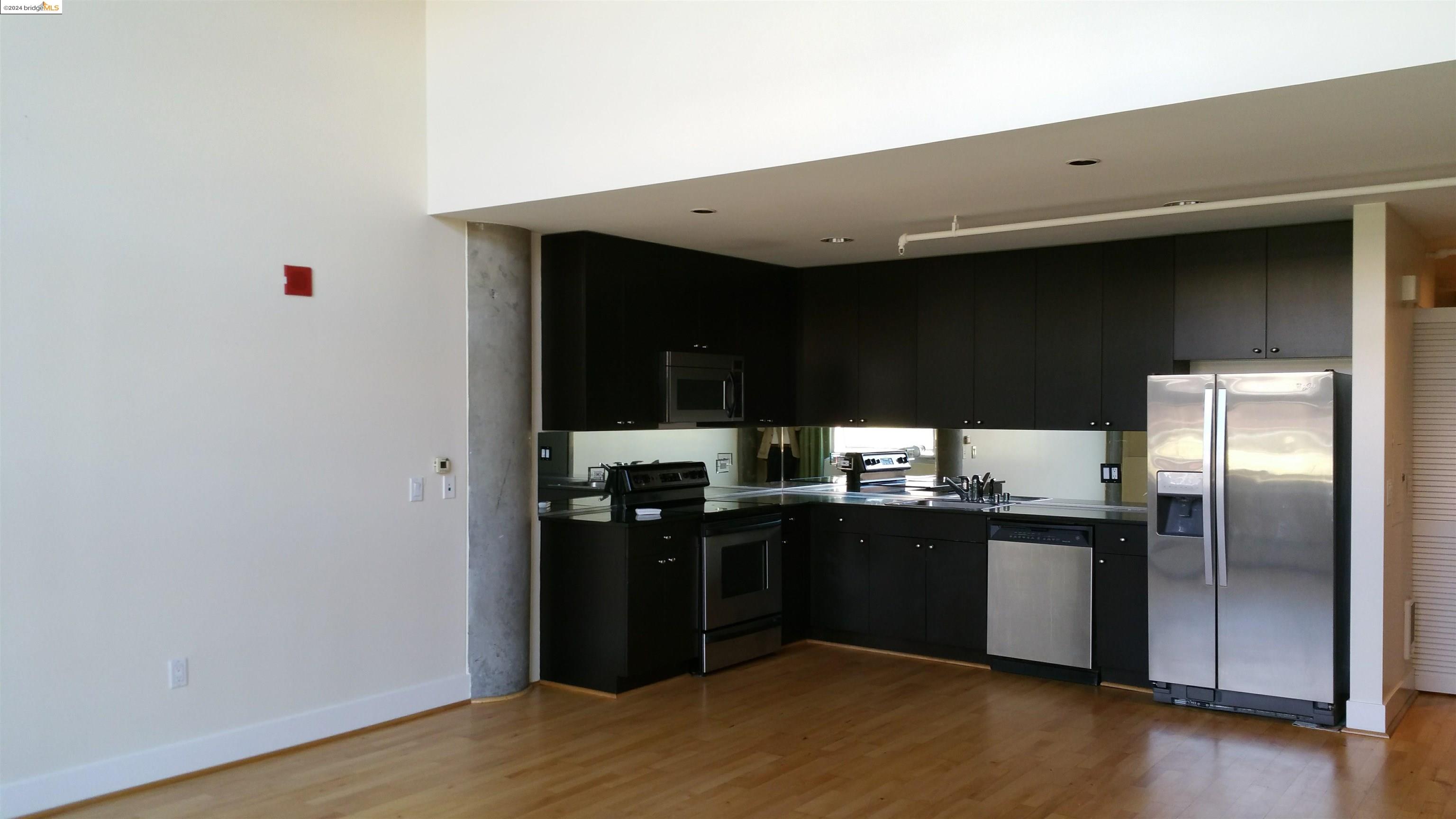 311 Oak Street, Unit 540 Oakland, CA 94607 - Photo 2 of 21 a kitchen with stainless steel appliances kitchen island granite countertop a refrigerator and a sink