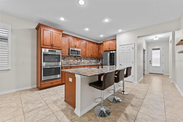 a kitchen with stainless steel appliances granite countertop a stove a sink a microwave a refrigerator and cabinets