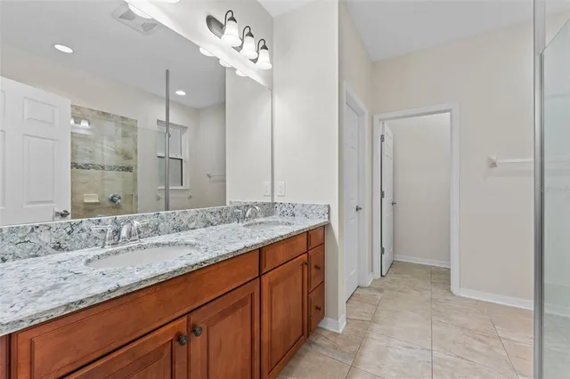 a spacious bathroom with a granite countertop sink a mirror and shower