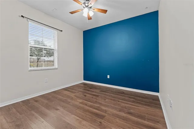 a view of empty room with wooden floor and fan