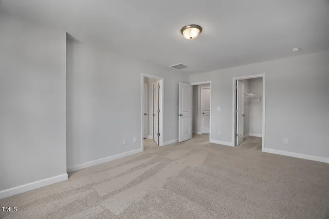 a view of an empty room with closet and a window