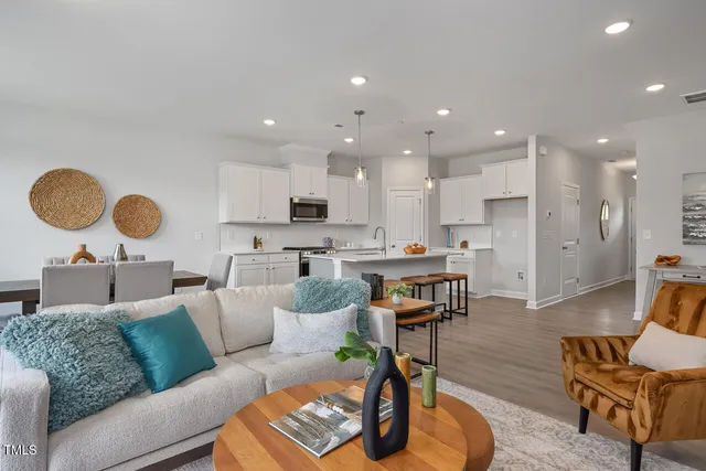 a living room with furniture kitchen view and a wooden floor