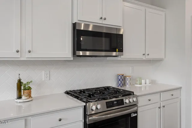 a kitchen with stainless steel appliances granite countertop white cabinets and a stove a oven with white countertops
