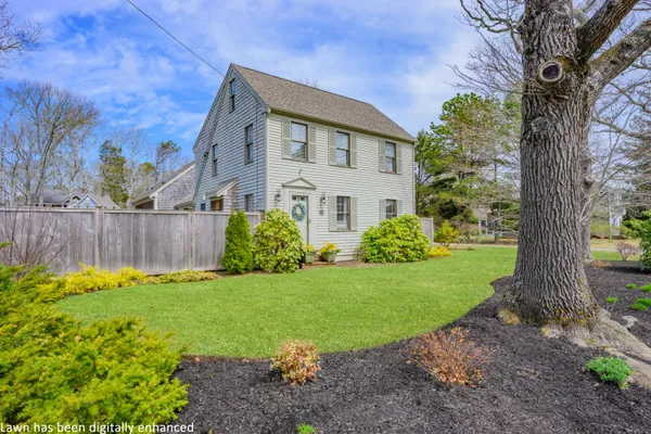 a view of a house with brick walls and a yard with plants and a bench