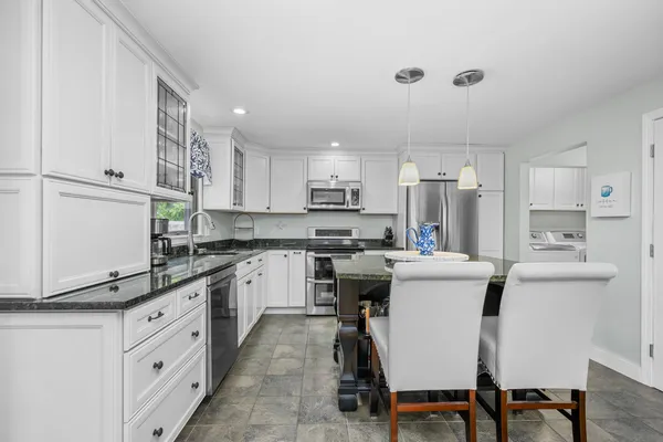 a kitchen with stainless steel appliances a refrigerator a stove a sink and white cabinets