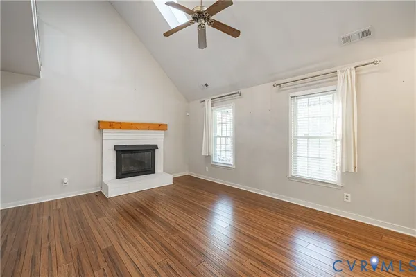 an empty room with wooden floor fireplace and windows