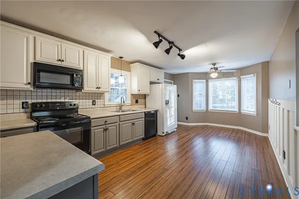 a kitchen with stainless steel appliances granite countertop wooden floors a stove a microwave and cabinets