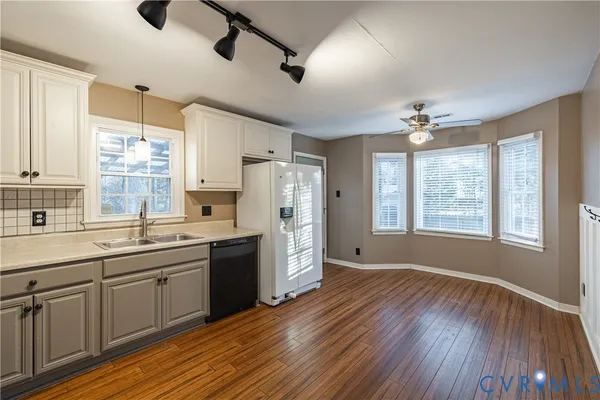a large kitchen with a center island wooden floor and stainless steel appliances