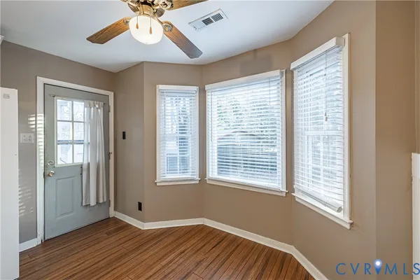 a view of an empty room with wooden floor and a window