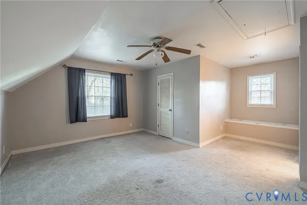 an empty room with windows and fan