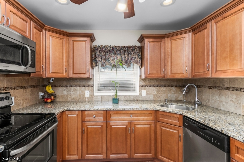 538 Vail Road Landing, NJ 07850 - Photo 7 of 26 a kitchen with granite countertop a sink stainless steel appliances wooden cabinets and a counter top space