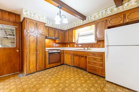 a kitchen with stainless steel appliances granite countertop a refrigerator a sink dishwasher a stove with white cabinets and wooden floor