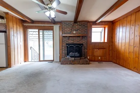 a view of an empty room with window and fire place