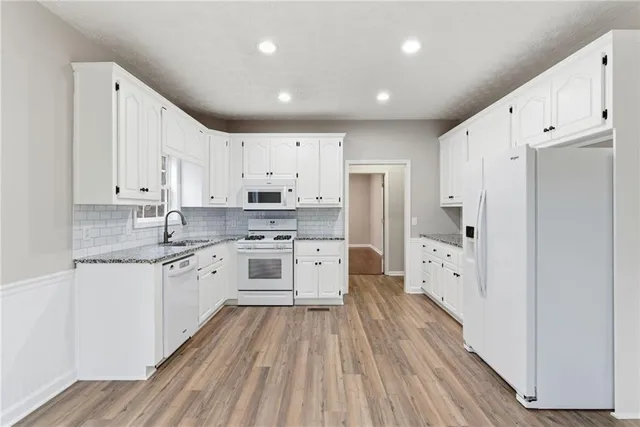 a large kitchen with stainless steel appliances a refrigerator and white cabinets