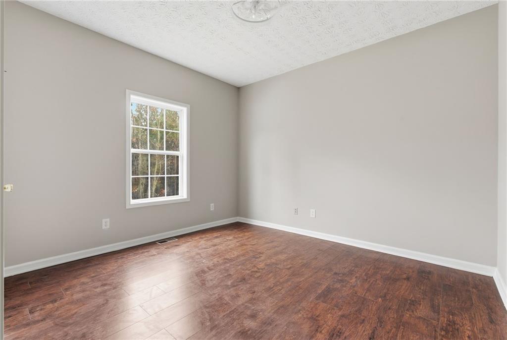 125 Nelson Oaks Drive Ball Ground, GA 30107 - Photo 18 of 41 an empty room with wooden floor and windows