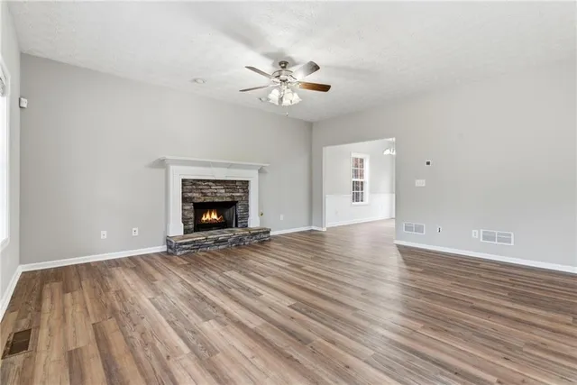 a view of an empty room with wooden floor and a fireplace