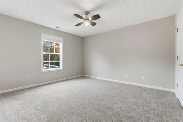 an empty room with windows and ceiling fan