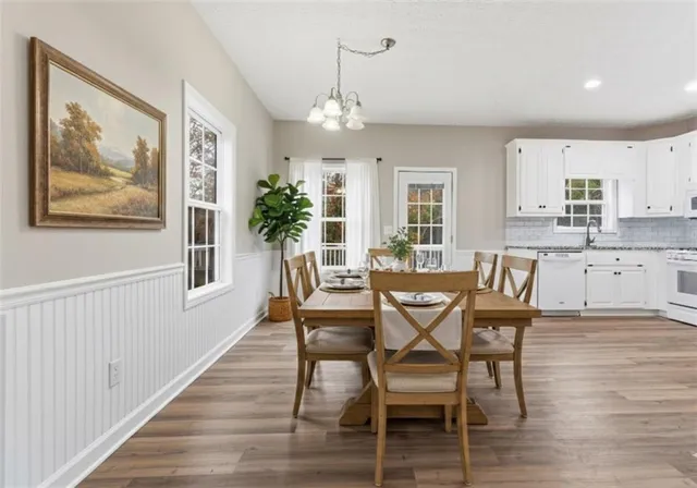 a dining room with wooden floor a chandelier a wooden table and chairs
