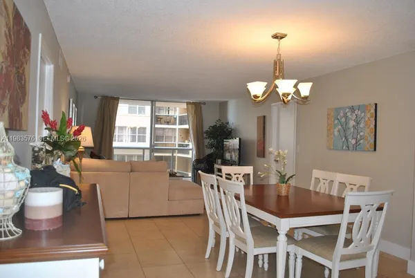 a view of a dining room with furniture a chandelier and large windows