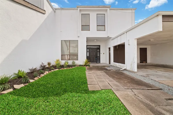 a view of a brick house with a yard and plants