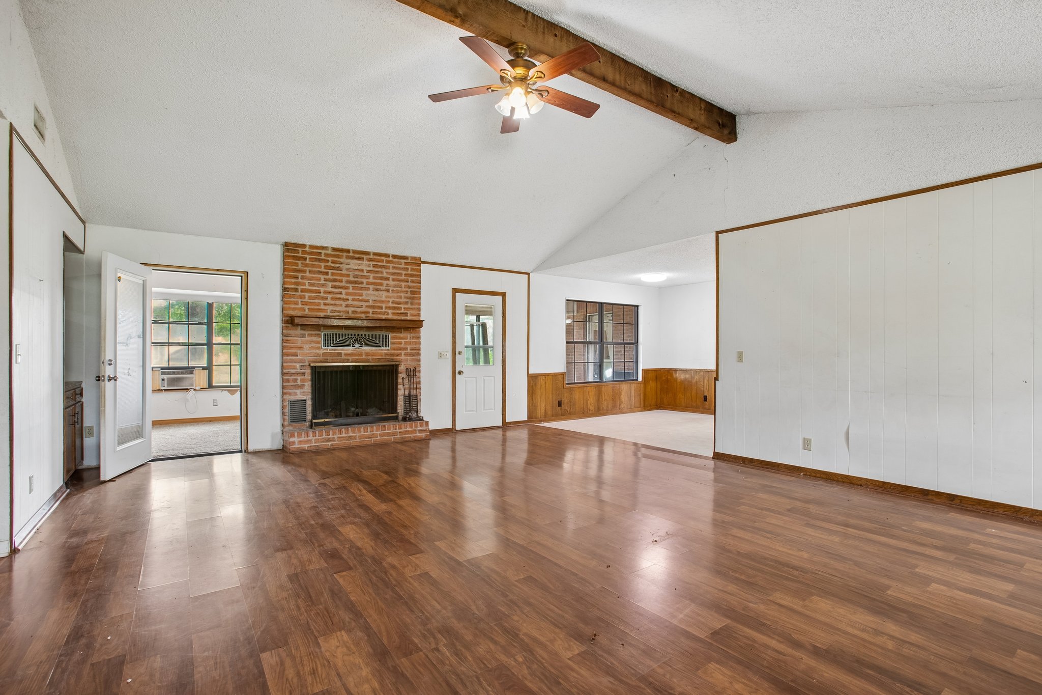 406 Monkey Road Elgin, TX 78621 - Photo 6 of 39 Spacious interior featuring wood-finish flooring, a brick fireplace with a wood mantle, vaulted ceilings with an exposed beam, and a ceiling fan