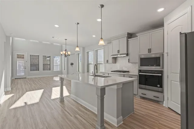 a kitchen with stainless steel appliances granite countertop a stove refrigerator and a wooden floors