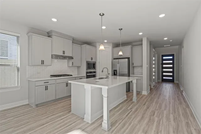 a large kitchen with kitchen island a sink stainless steel appliances and cabinets